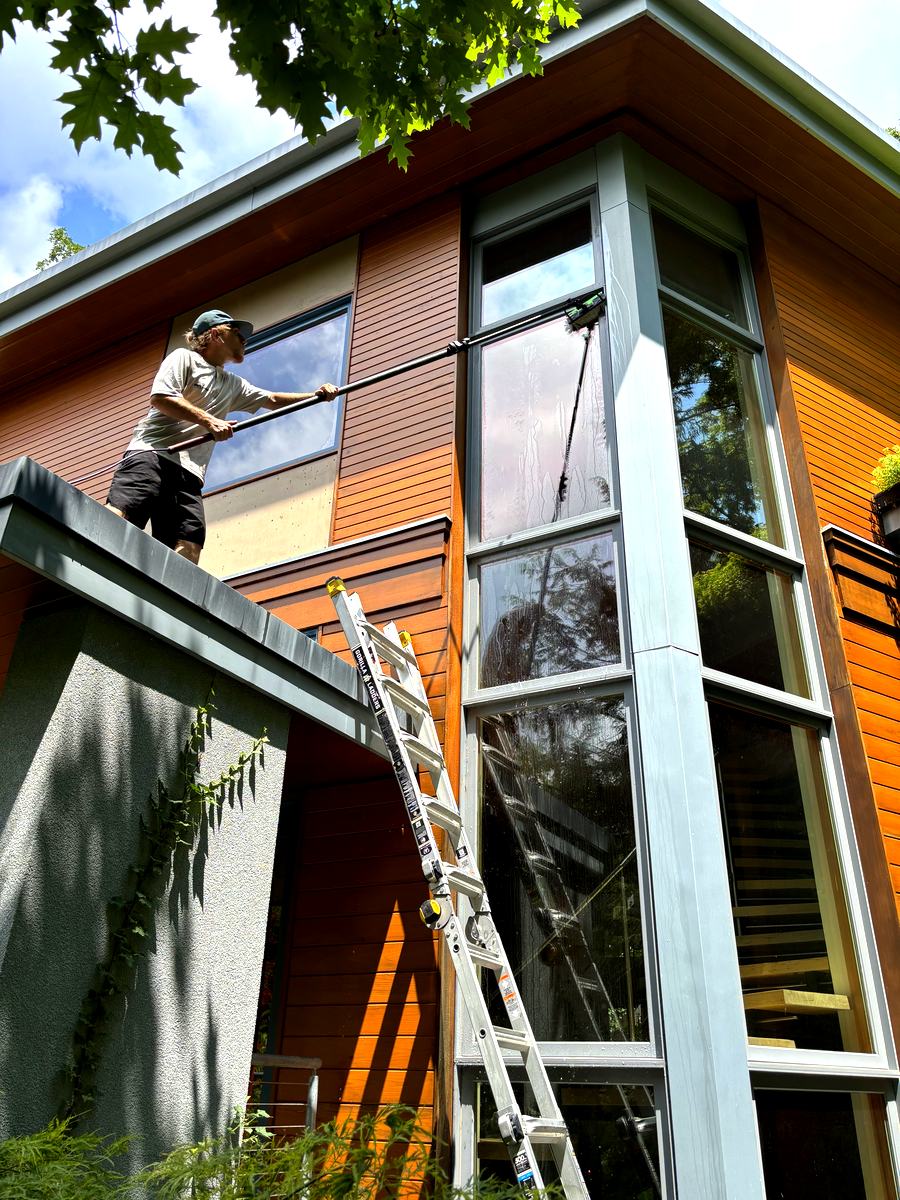 Cleaning tall windows on a modern home from the roofline